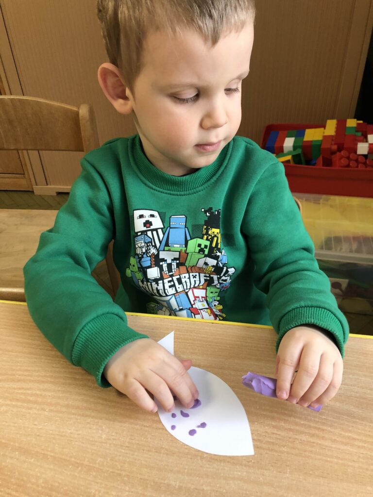Chłopiec wykleja kształt ryby bibułką.