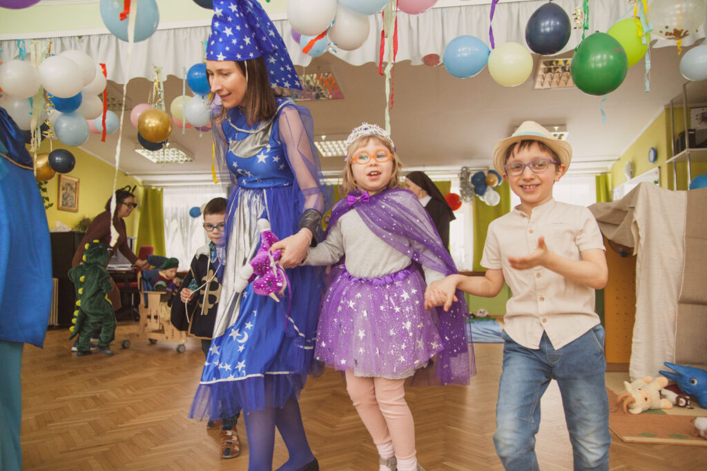 Przebrana nauczycielka obok przebrane dzieci.