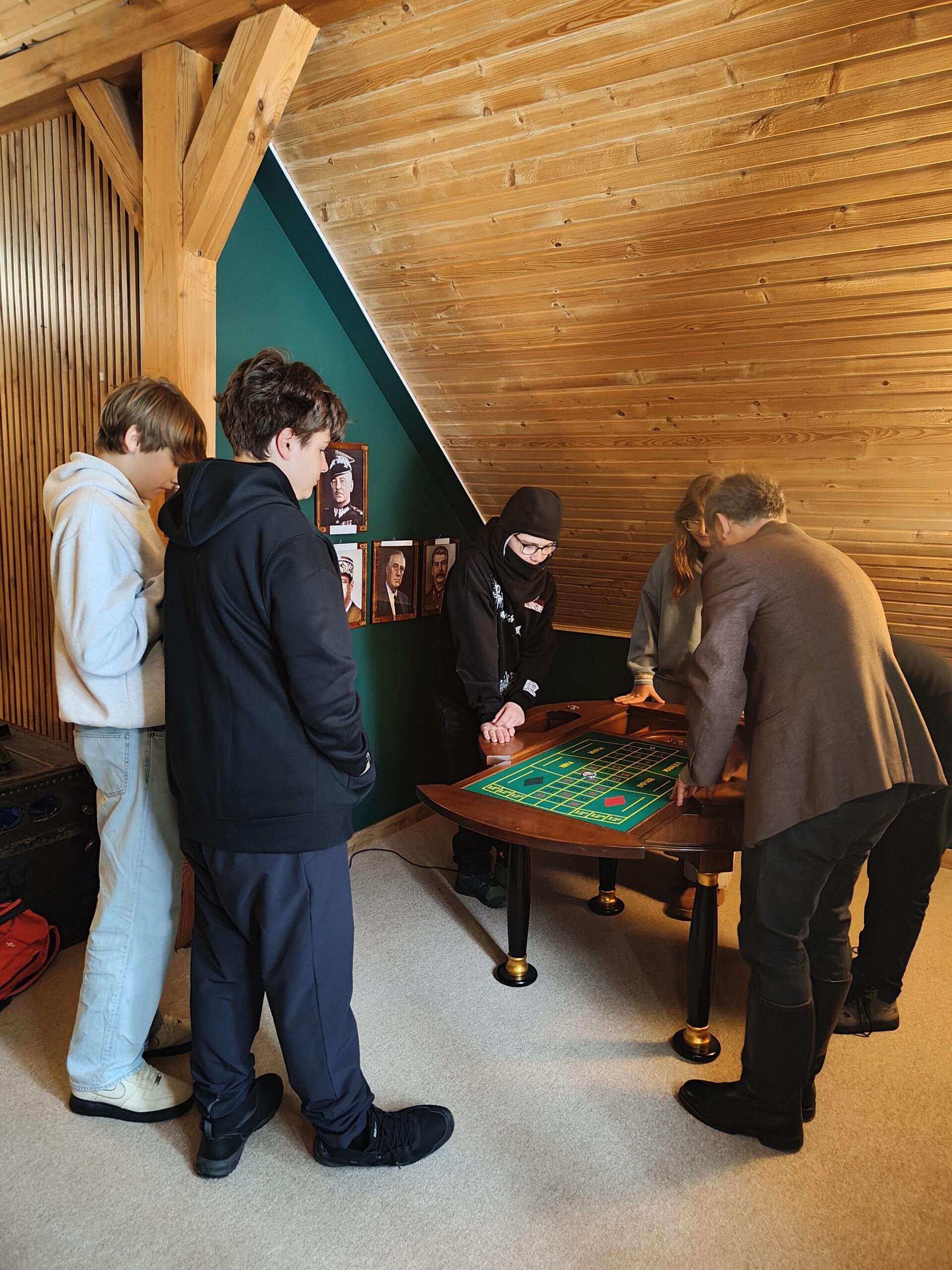 Uczniowie z nauczycielem pochylają się nad stołem z zadaniami