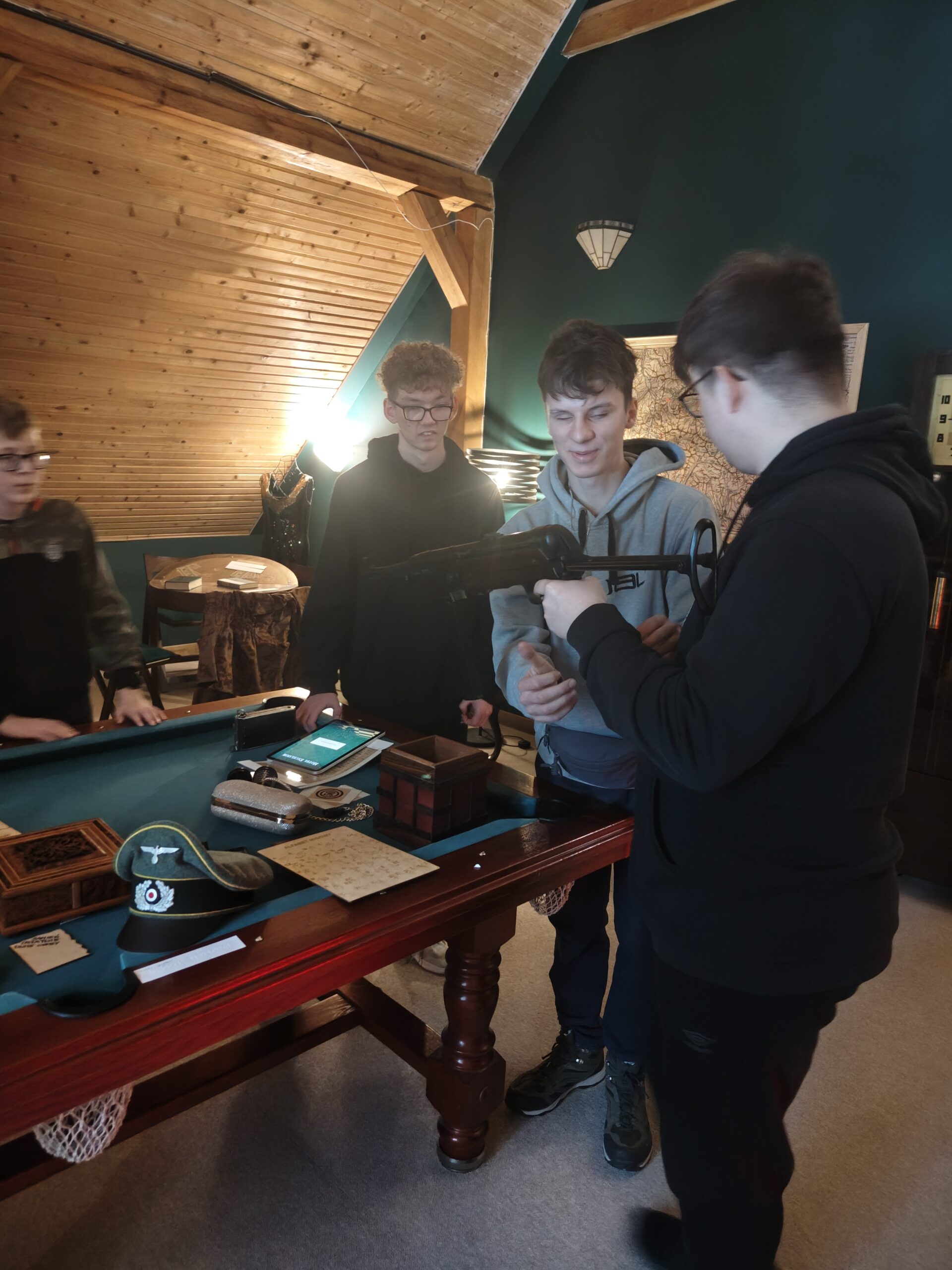 Jeden uczeń trzyma karabin, dwóch innych stoi obok niego