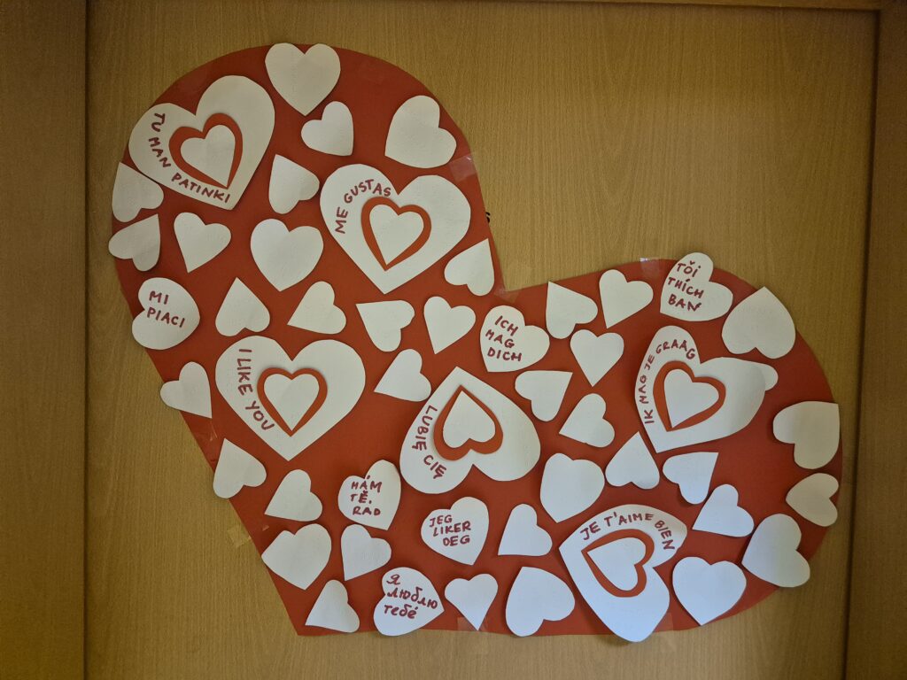 Ogromne serce zawieszone na drzwiach w grupie V . Na sercu umieszczone zostały w różnych językach wyznania miłosne " kocham Cię"