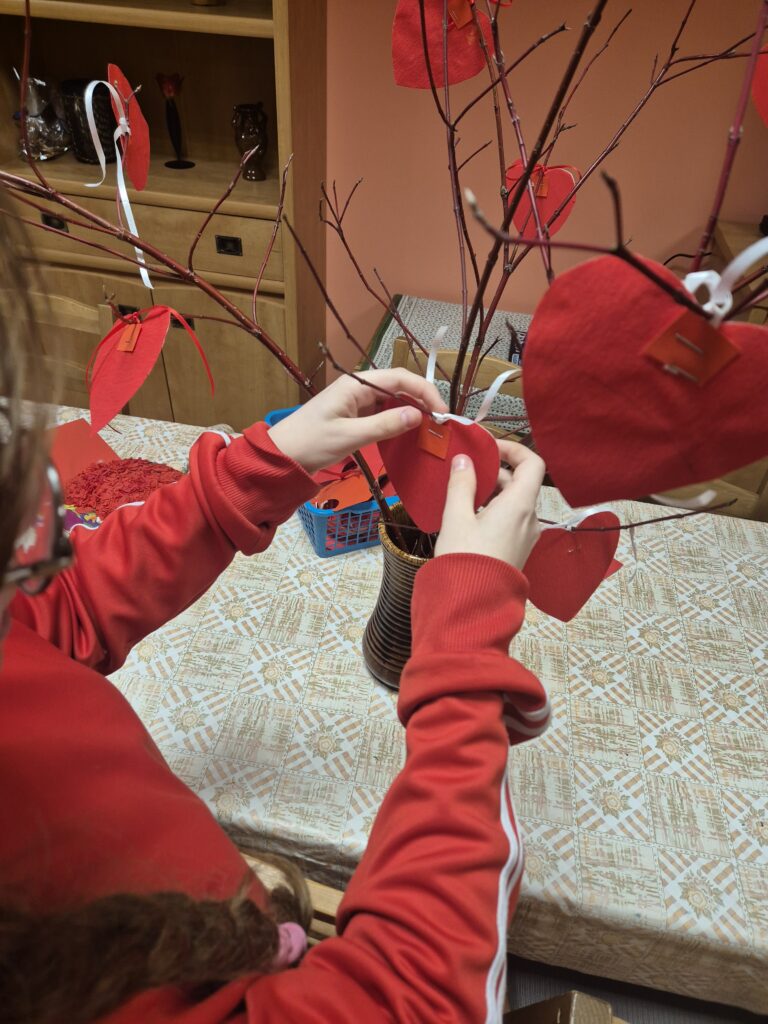 Julia zawiesza czerwone serduszka na drzewie miłości