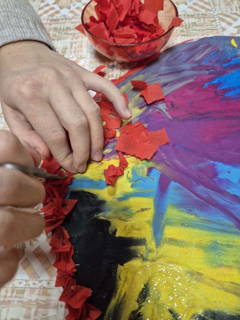 Na wyklejonym sercu Nikola wbija szpikulcem kawałki czerwonej bibuły