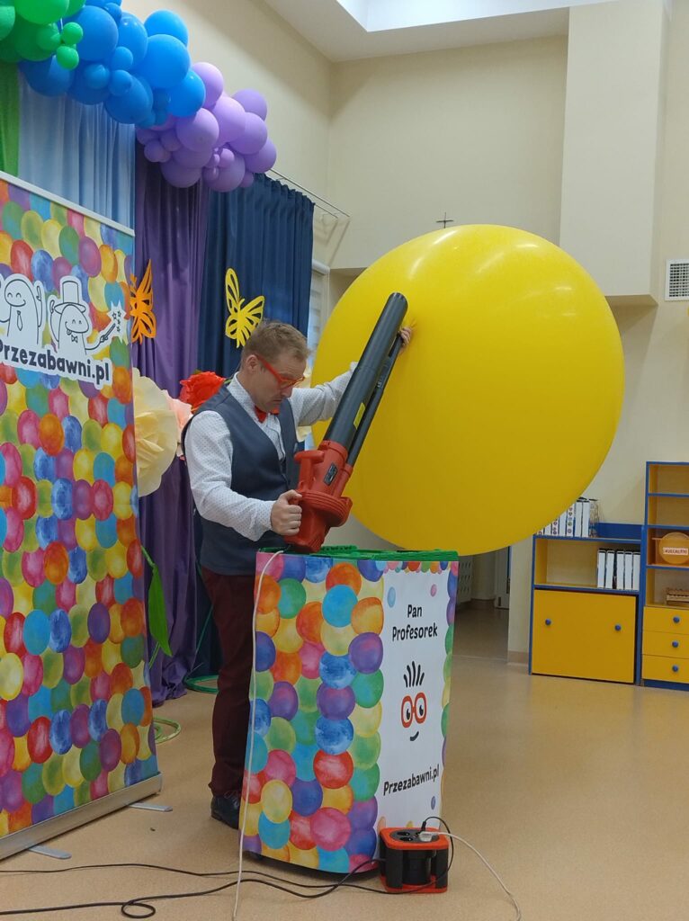 Pan pompuje ogromny balon dmuchawą do lości