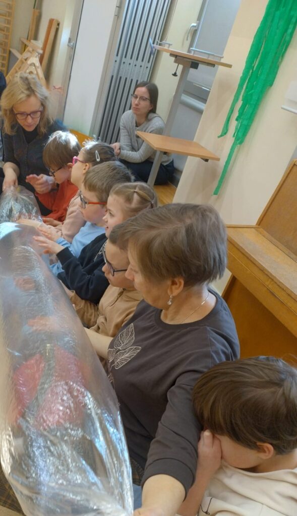 Dzieci z długim balonem z torby foliowej na kolanach