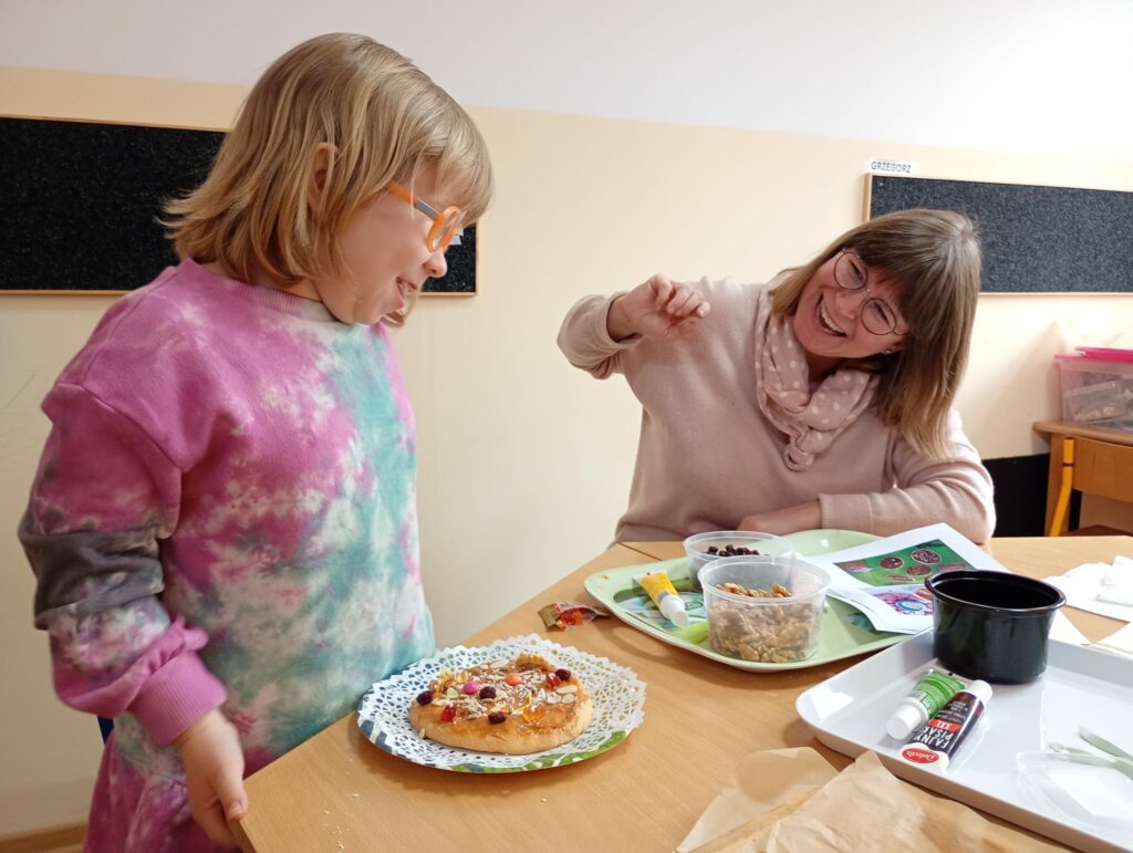 Dziewczynka z mamą ozdabiają mazurek.