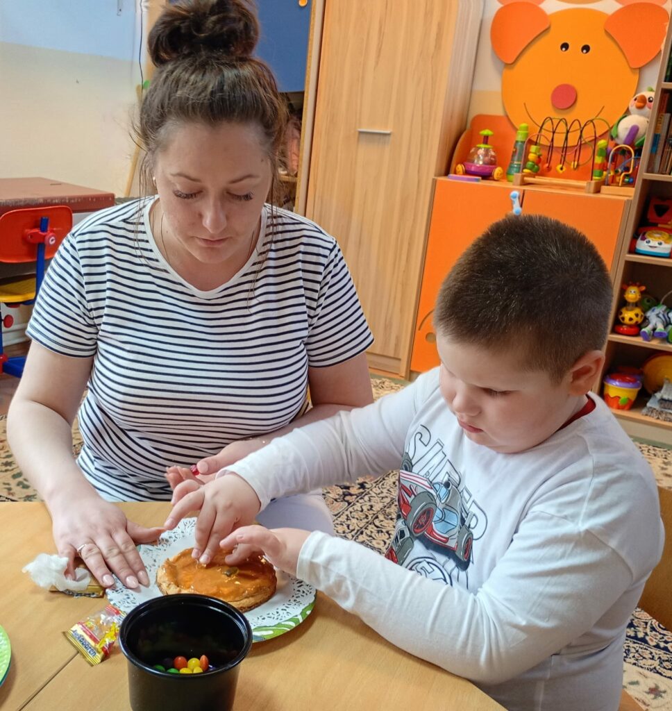 Chłopiec z mamą ozdabia mazurek.