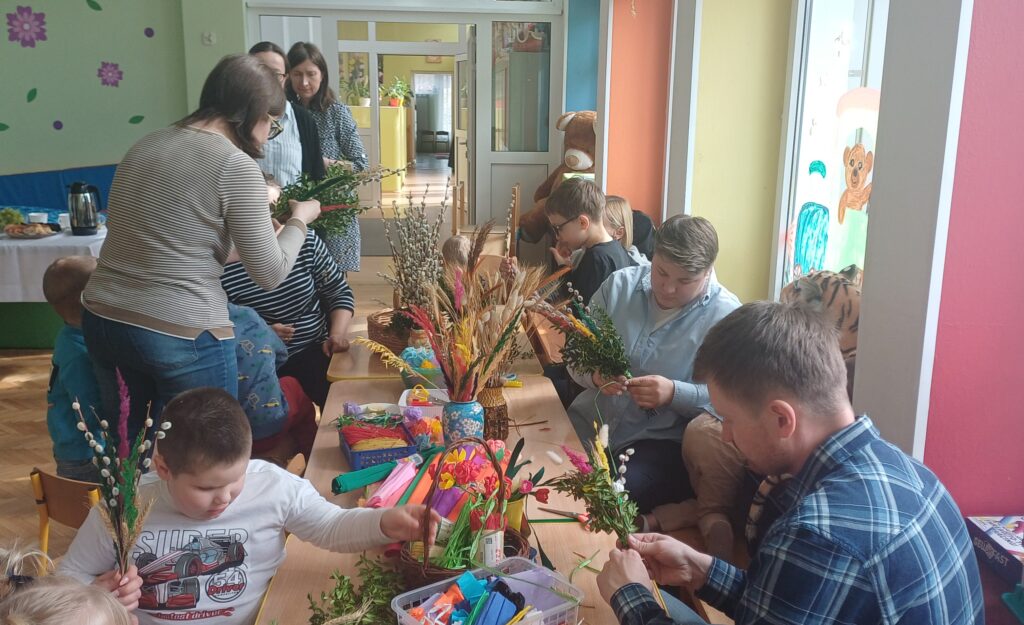 Dzieci i rodzice przy stole tworzą palmy.