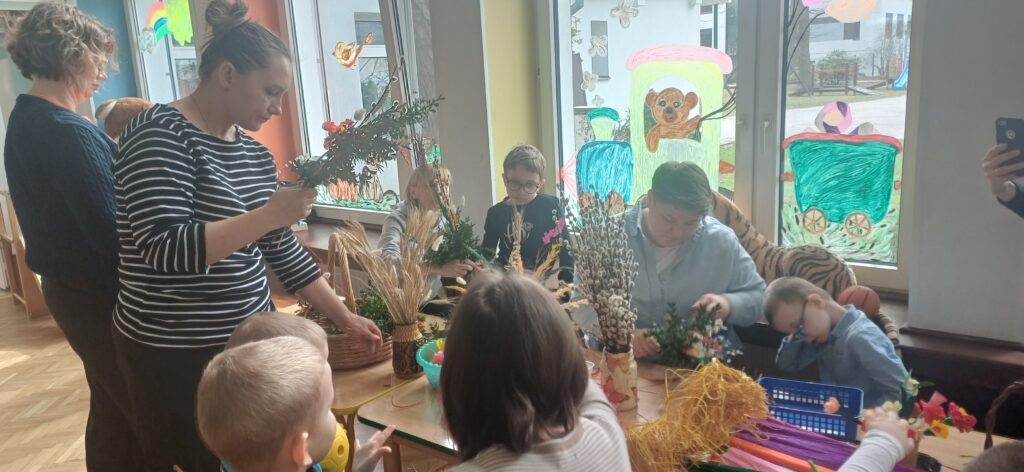 Dzieci i rodzice przy stole tworzą palmy.