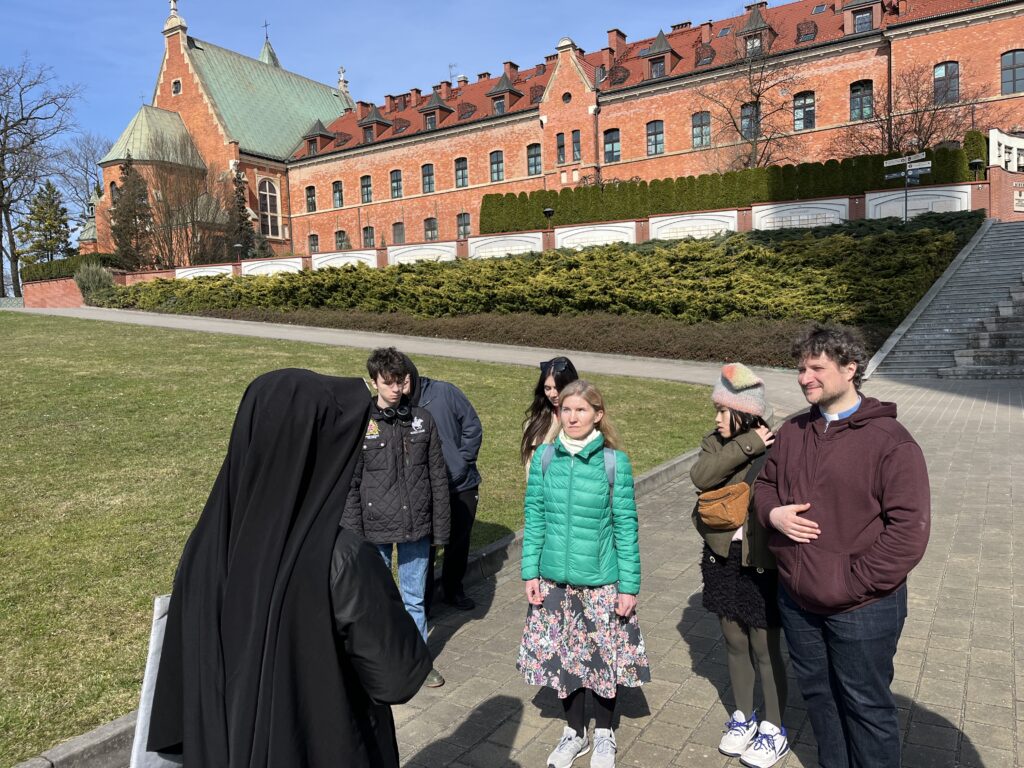 Na dziedzińcu Sanktuarium Miłosierdzia Bożego w Krakowie-Łagiewnikach, w otoczeniu zabytkowej architektury klasztornej, maturzyści oraz ich opiekunowie kontynuowali spotkanie z siostrą zakonną. 