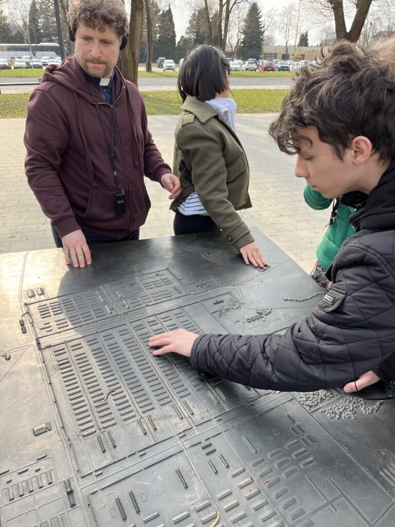 Podczas zwiedzania Miejsca Pamięci, maturzyści wraz z księdzem rektorem zatrzymali się przy makiecie prezentującej ogromny obszar obozu Auschwitz II-Birkenau. Analiza tego modelu pozwoliła uczestnikom uświadomić sobie skalę tragedii oraz topografię miejsca, które za chwilę mieli zobaczyć na własne oczy. To fizyczne zetknięcie z planem obozu stanowiło istotne wprowadzenie do zrozumienia historii tego miejsca.