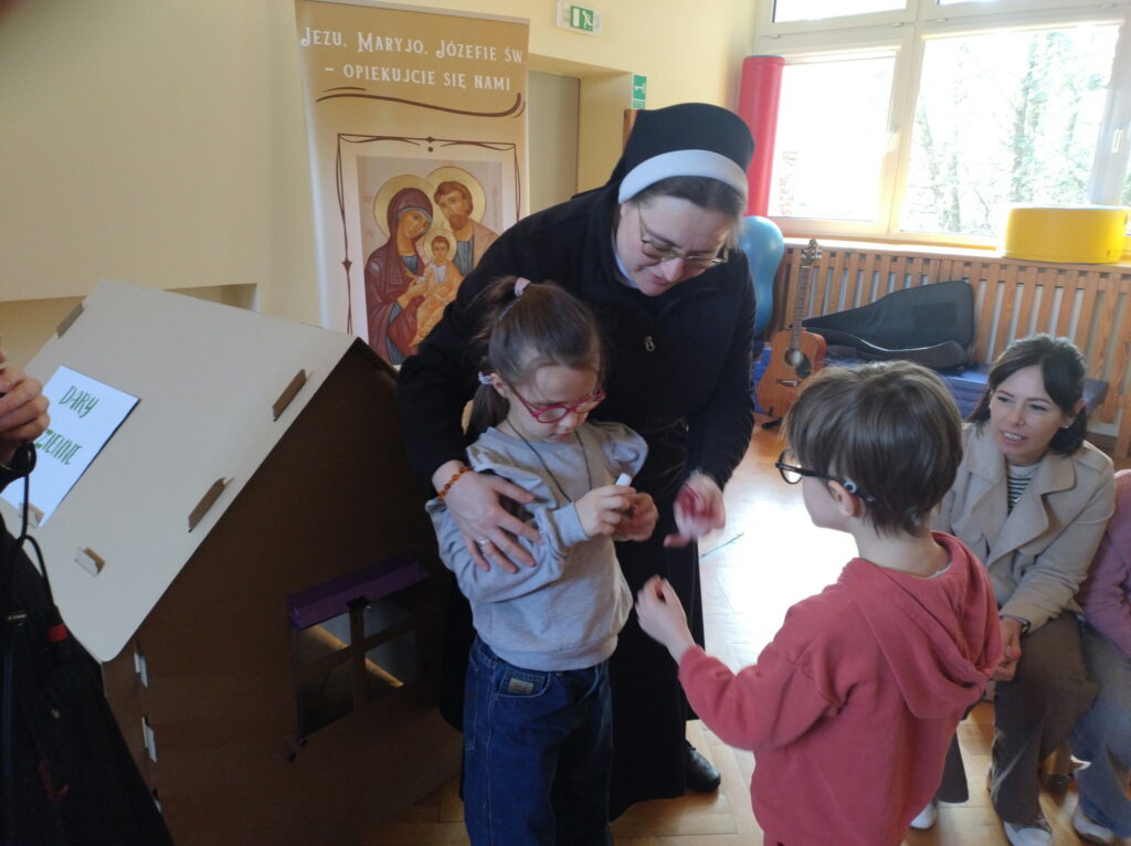 Najmłodsi uczniowie obok tekturowego domku