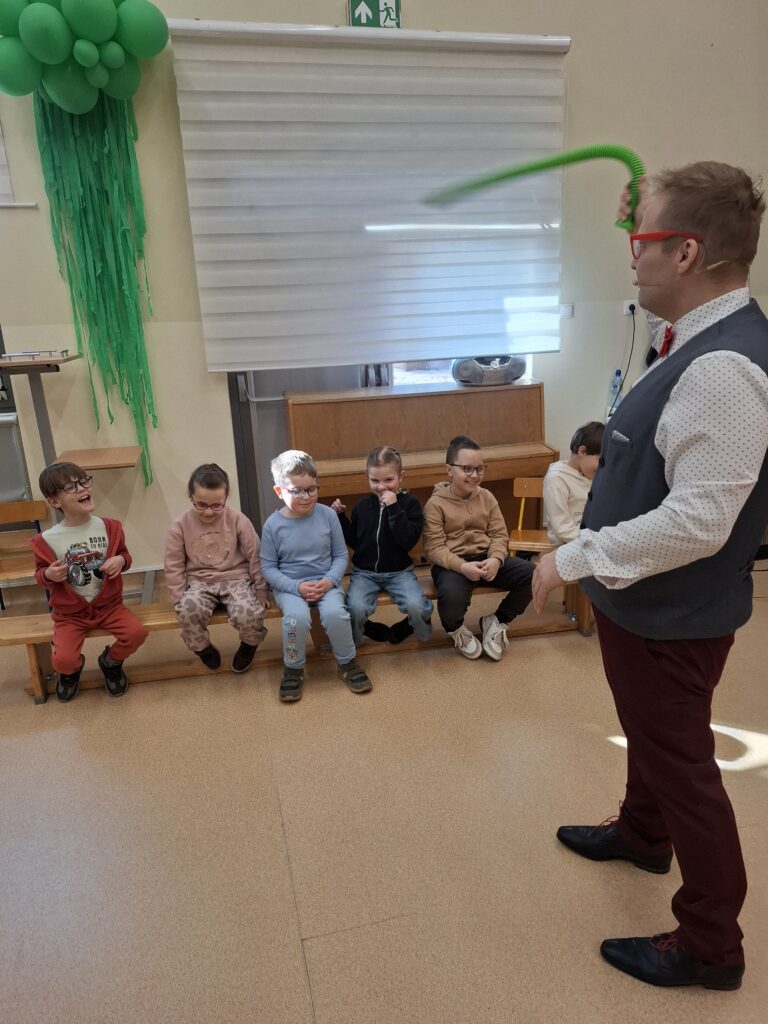 Prowadzący macha rozciągliwą rurką, która wydaje dźwięk