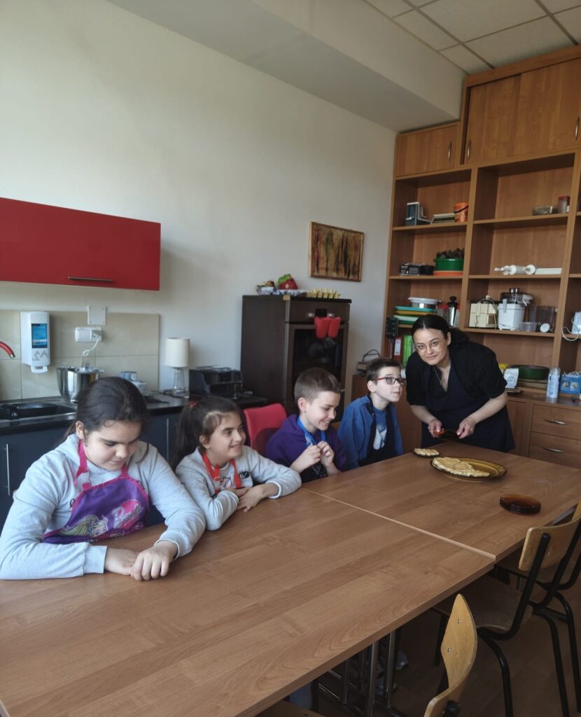 Uczniowie klasy drugiej z panią psycholog w kuchence dydaktycznej