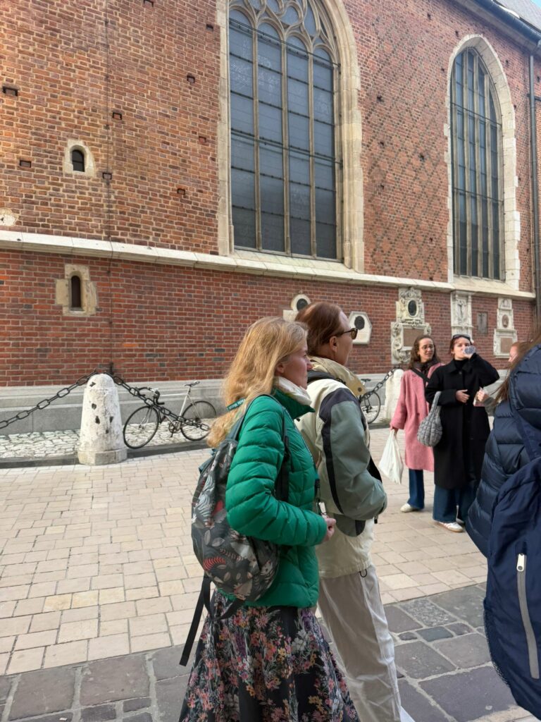 Uczestniczki wycieczki podziwiają architekturę krakowskiego Starego Miasta, co było częścią programu zwiedzania najważniejszych zabytków Krakowa, takich jak Kościół Mariacki czy Sukiennice.