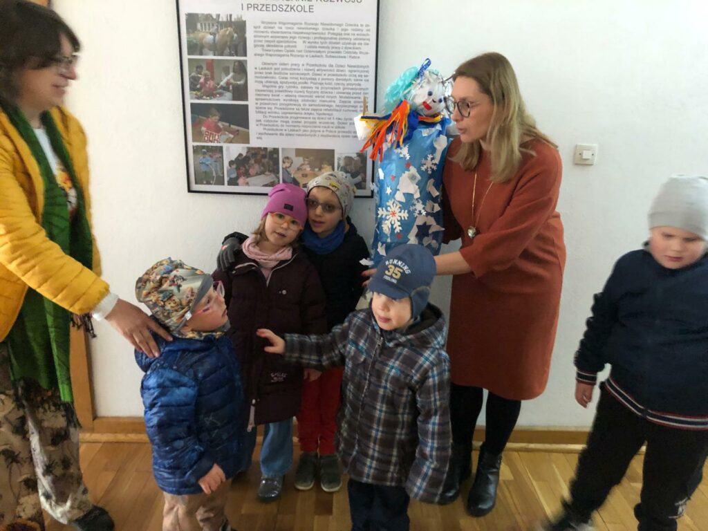 Pani Dyrektor trzyma panią zimę obok stoją przedszkolaki