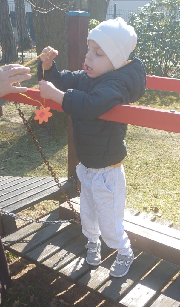 Chłopiec trzyma sznurek na którym wisi kwiatek.