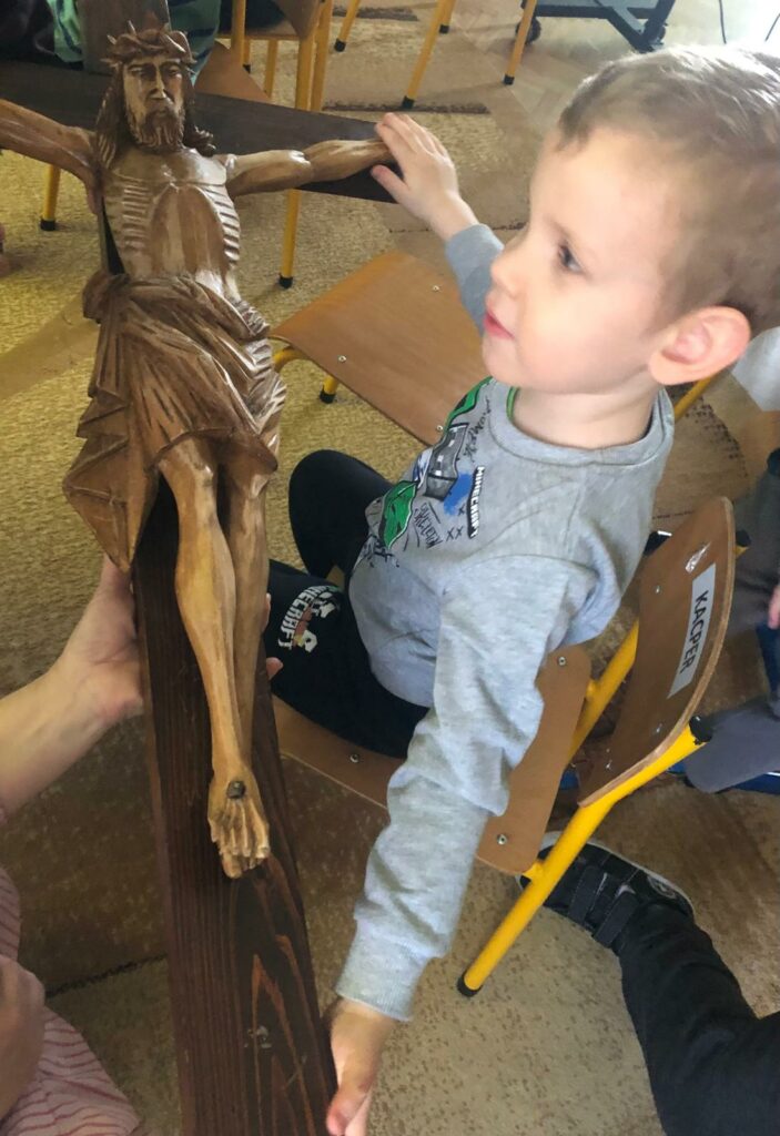 Chłopiec dotyka figury Pana Jezusa na krzyżu