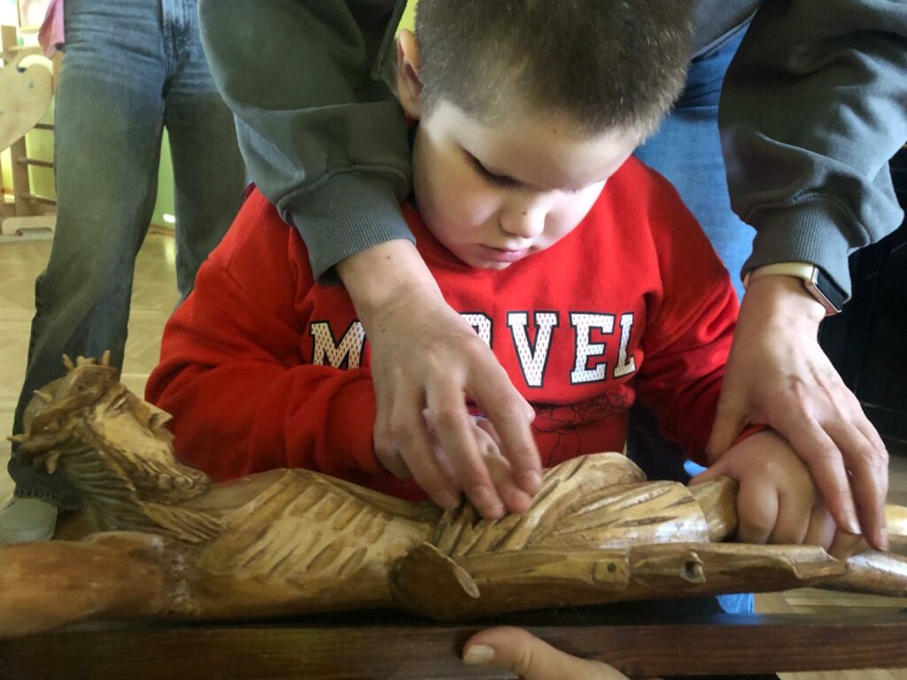 Chłopiec dotyka leżącej figury Pana Jezusa