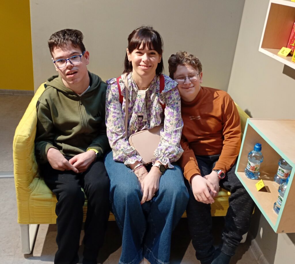 Dwaj chłopcy z wychowawczynią siedzą na kanapie.