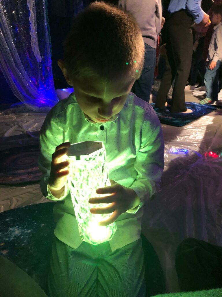 Chłopiec trzyma w rękach świecącą lampę.