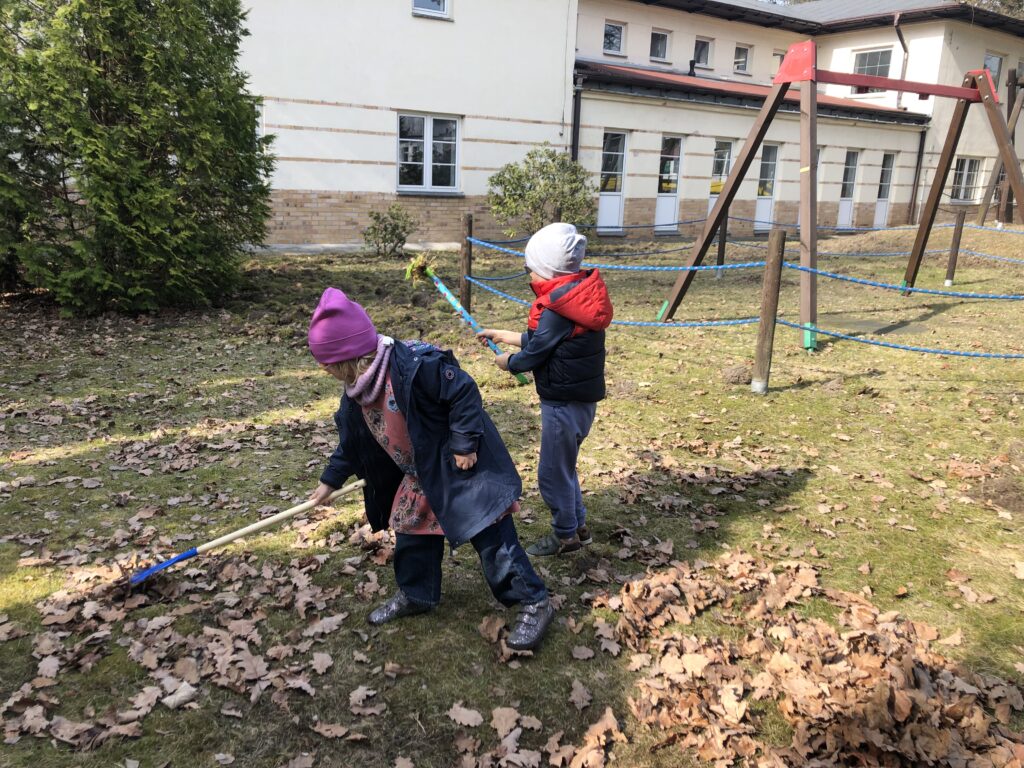 Dziewczynka i chłopiec grabią liście.