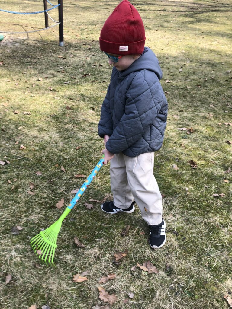 Chłopiec grabi liście.