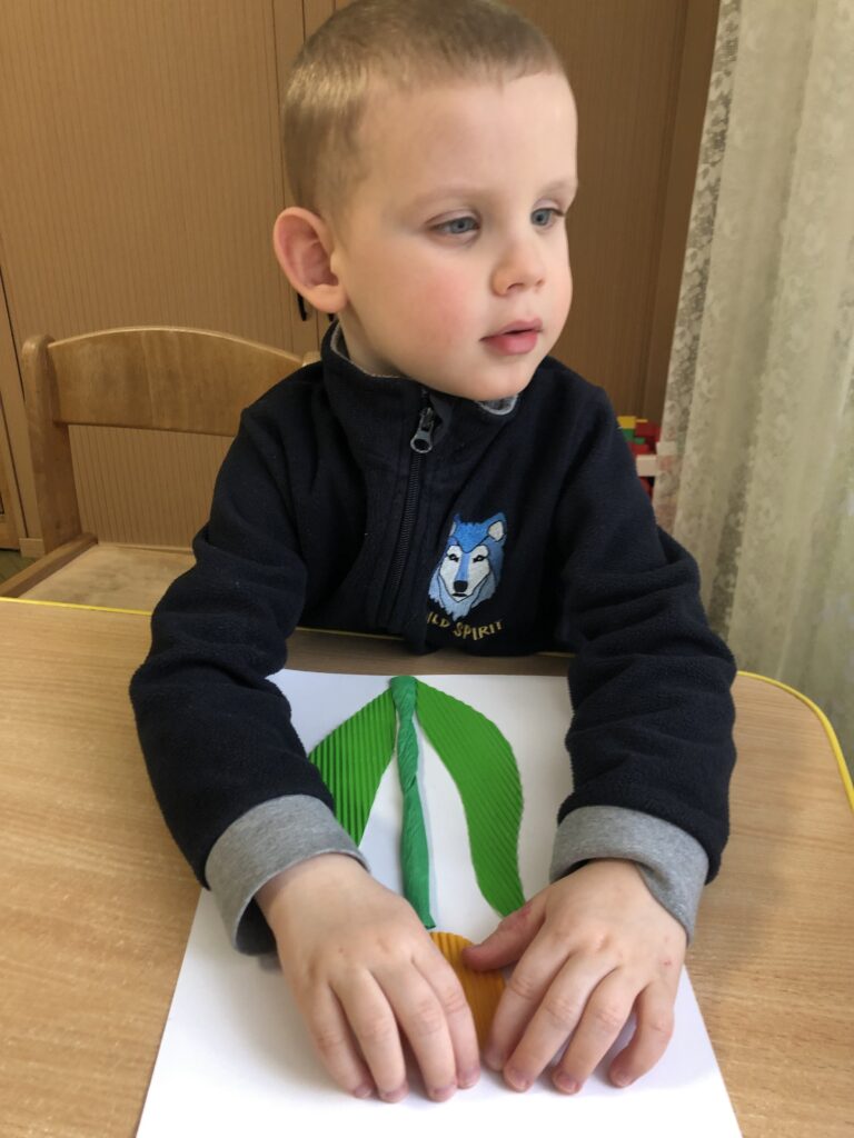 Chłopiec dotyka naklejonego papierowego modelu tulipana.