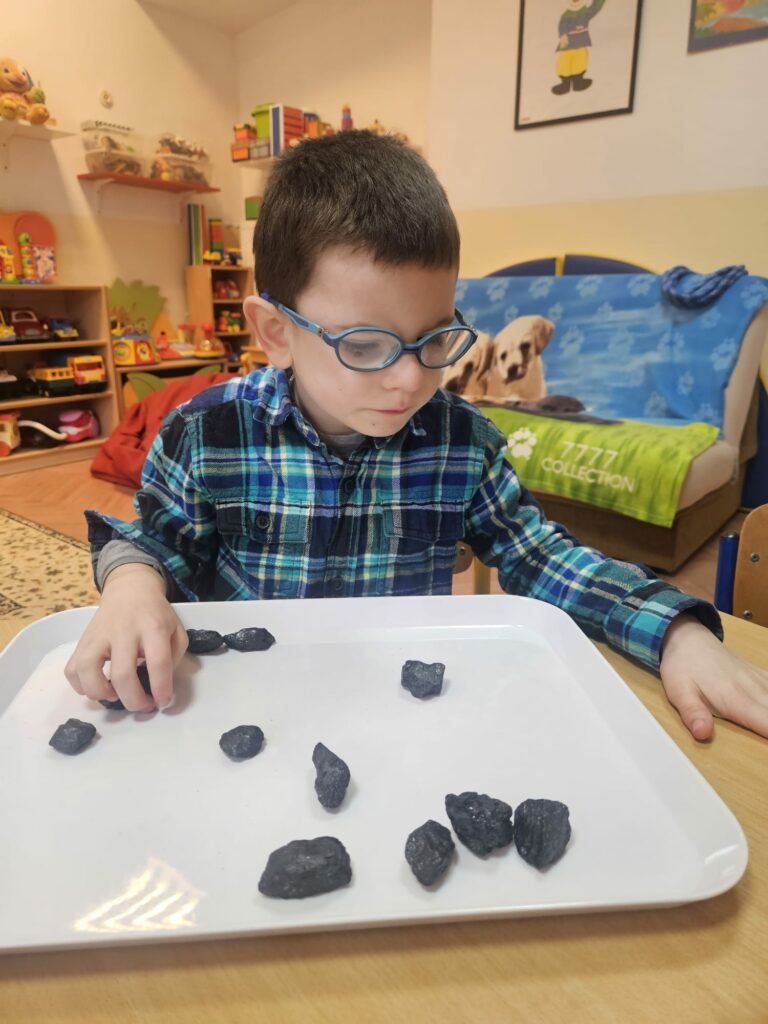 Chłopiec ogląda bryłki węgla.