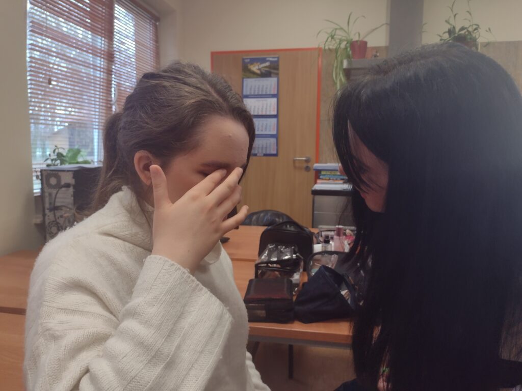 
Pod czujnym okiem instruktorki, uczennica w białym swetrze samodzielnie i z wyczuciem sprawdza palcami gładkość nałożonego na powiekę kosmetyku, ucząc się precyzyjnego blendowania podczas zajęć.