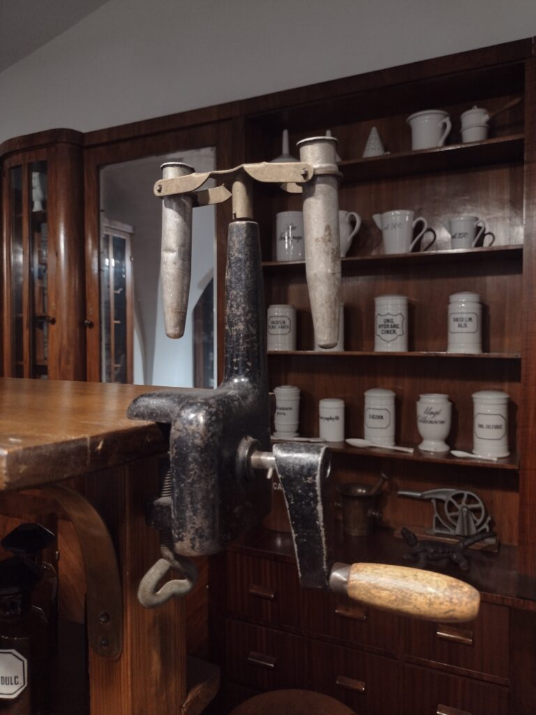 Zabytkowa wirówka ręczna przymocowana do blatu oraz rzędy dawnych naczyń aptecznych na regałach to niezwykłe eksponaty, które uczniowie mogli podziwiać podczas poznawania historii farmacji w muzeum.