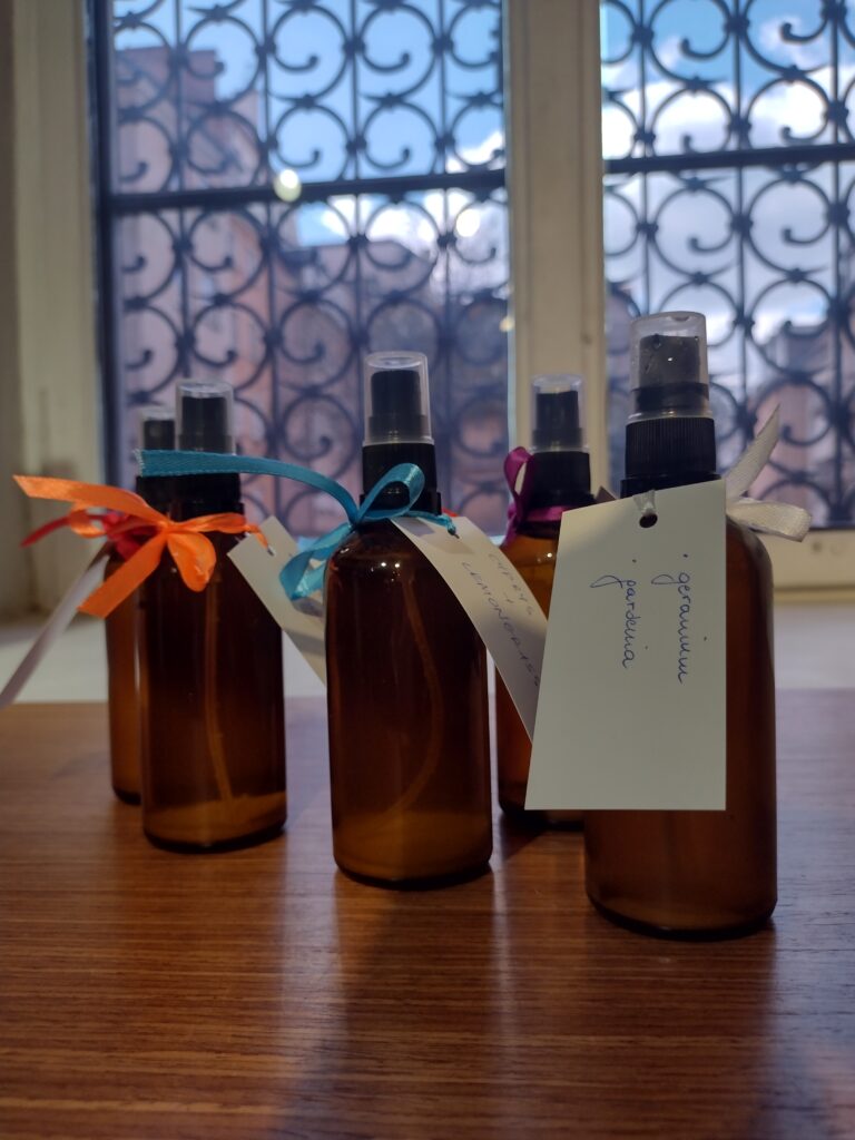 Gotowe buteleczki z wodami zapachowymi, ozdobione kolorowymi wstążkami i bilecikami z nazwami takimi jak „geranium” czy „gardenia”, prezentują się dumnie na tle muzealnego okna jako efekt końcowy twórczej pracy uczniów.