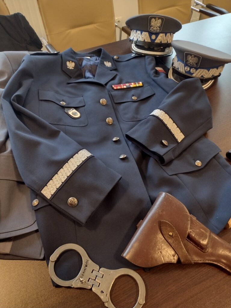 Uczestnicy wycieczki pozują do wspólnego zdjęcia pamiątkowego w Wydziale Edukacji Historycznej GKGP, dumnie prezentując otrzymane dyplomy i certyfikaty po zakończonej lekcji o historii Policji Państwowej.