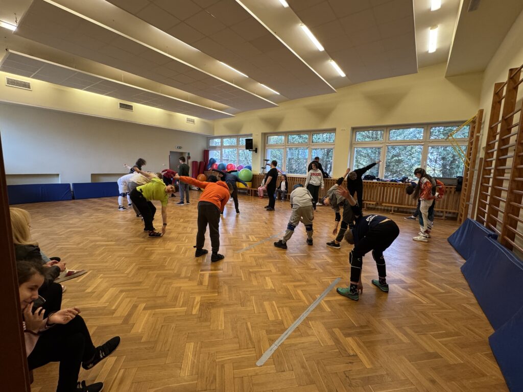 
Uczniowie biorą udział we wspólnej rozgrzewce na sali gimnastycznej, przygotowując swoje ciała do intensywnego wysiłku i sportowej rywalizacji podczas turnieju goalballa.