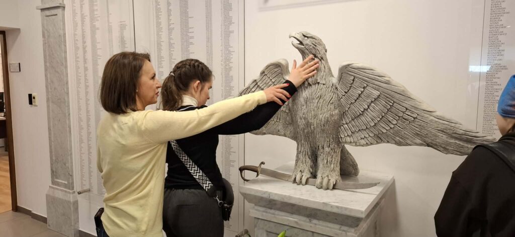 Podczas wizyty w Wydziale Edukacji Historycznej GKGP uczestniczki mają okazję bezpośrednio dotknąć historii, poznając detale rzeźby orła państwowego oraz dawnych atrybutów policyjnych.