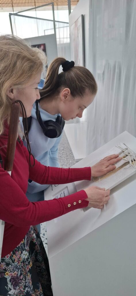 Uczennice w skupieniu poznają wystawę „Gero Hellmuth. Przeciw zapomnieniu”, wykorzystując przygotowane przez artystę tyflografiki, które pozwalają osobom niewidomym i słabowidzącym doświadczać sztuki poprzez zmysł dotyku.