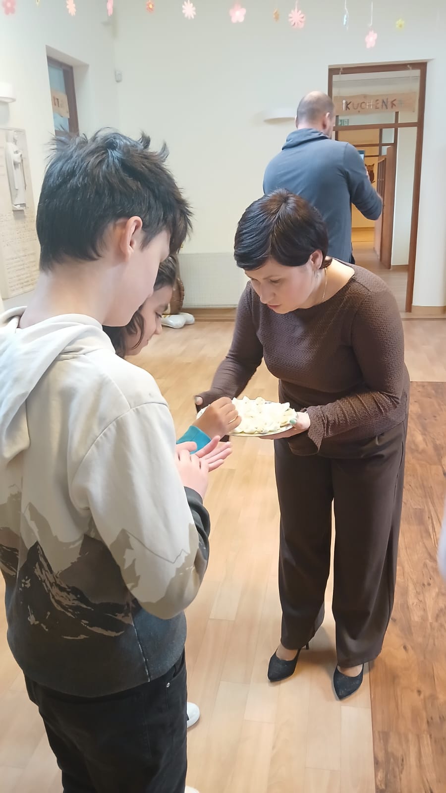 Pani Dyrektor z talerzem, obok dwóch uczniów częstujących się