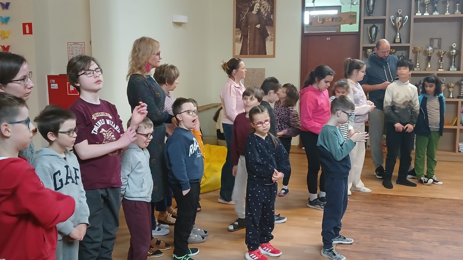Uczniowie i nauczyciele stojący w hallu podczas składania życzeń
