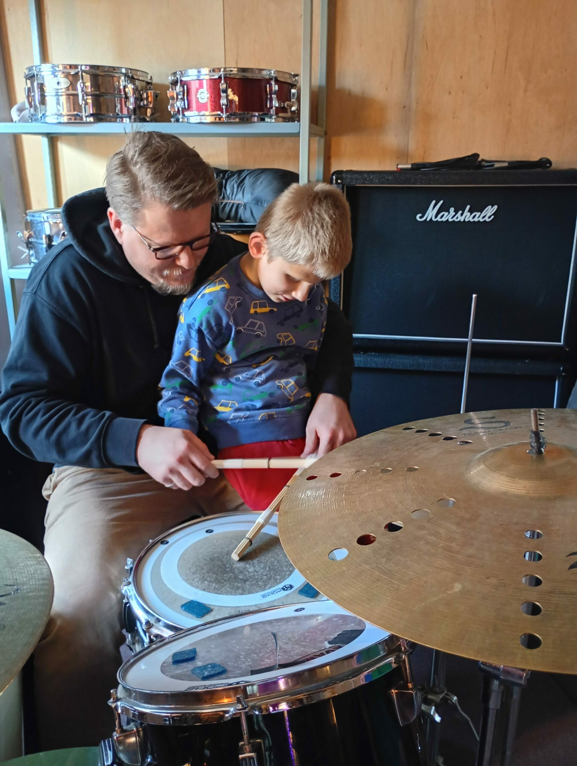 Chłopiec z instruktorem siedzą przy perkusji