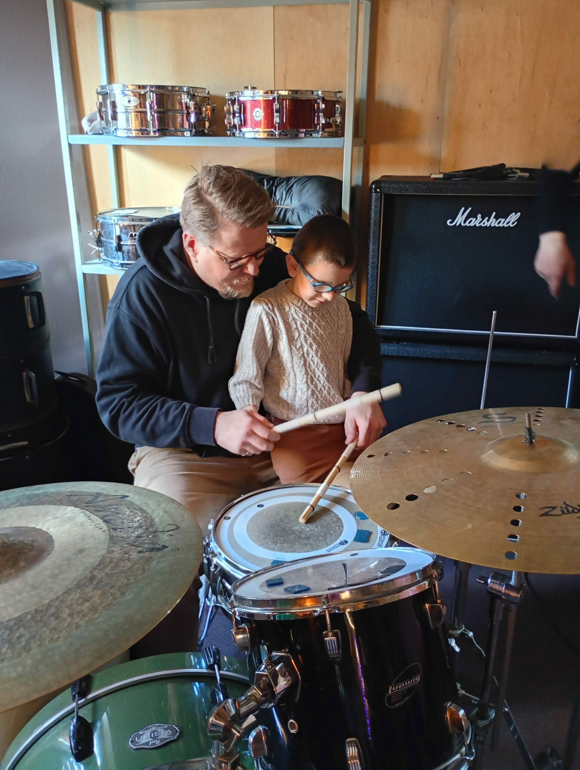 Chłopiec z instruktorem siedzą przy perkusji