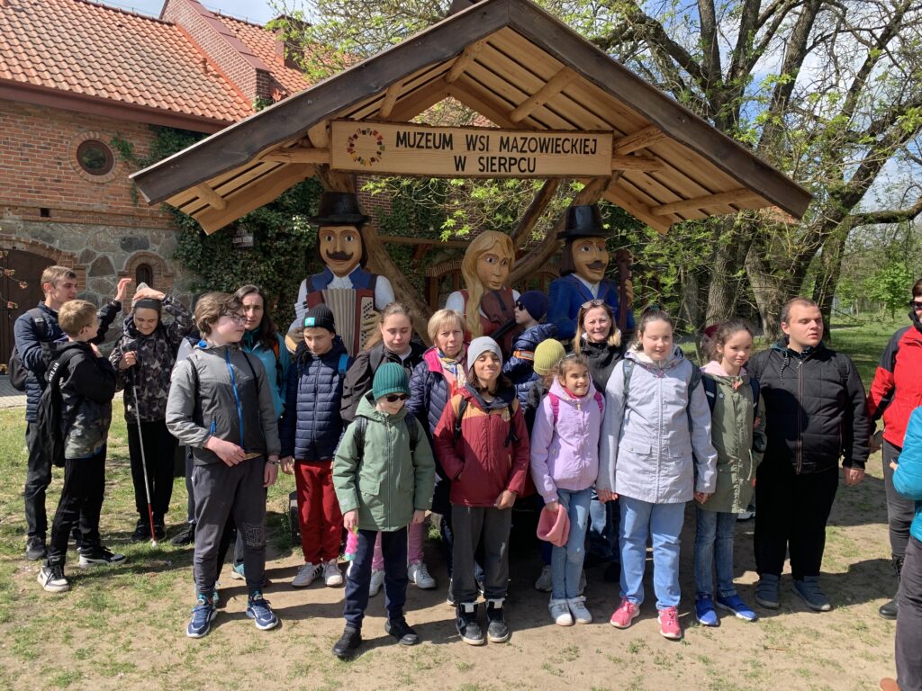 Cała grupa przy rzeźbach w strojach ludowych