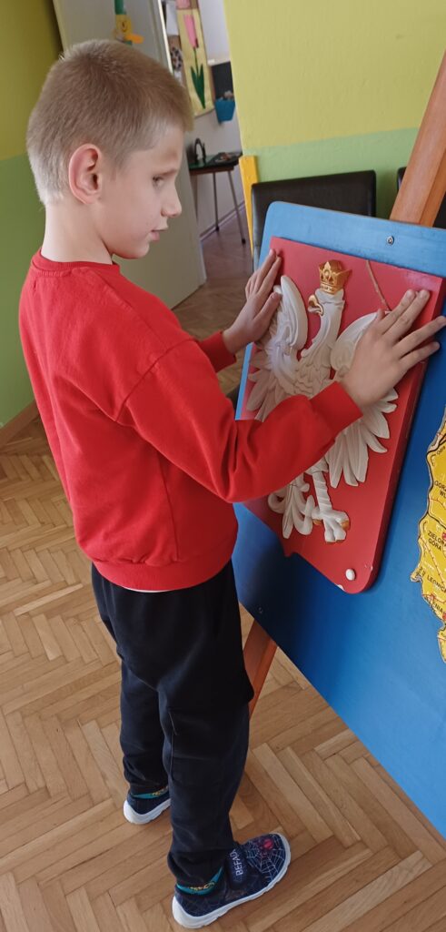 Chłopiec ogląda wypukłe godło Polski.