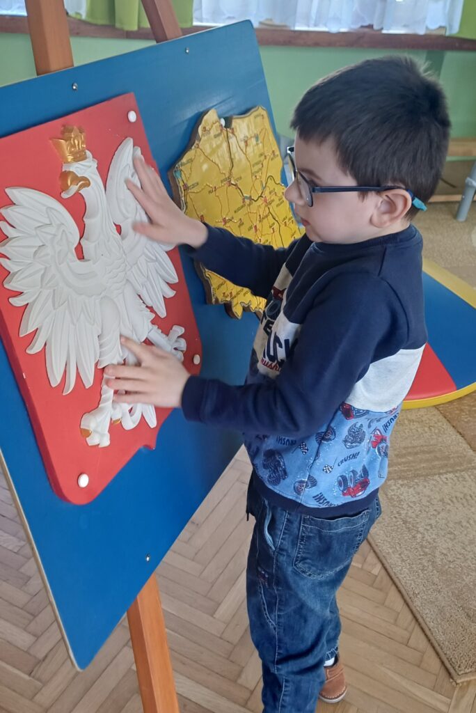 Chłopiec ogląda wypukłe godło Polski.
