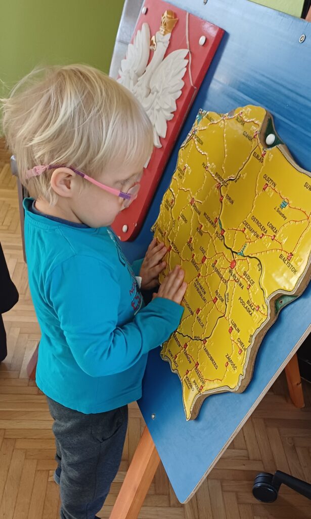 Chłopiec ogląda wypukłą mapę Polski.