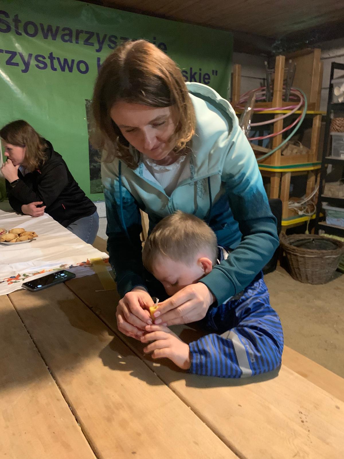 Uczeń klasy 3 robi świecę z pomocą nauczycielki