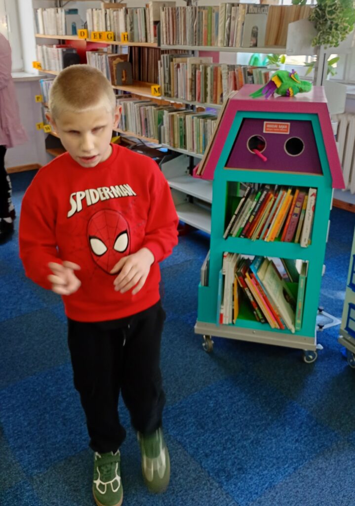 Stojący chłopiec na tle półek z książkami