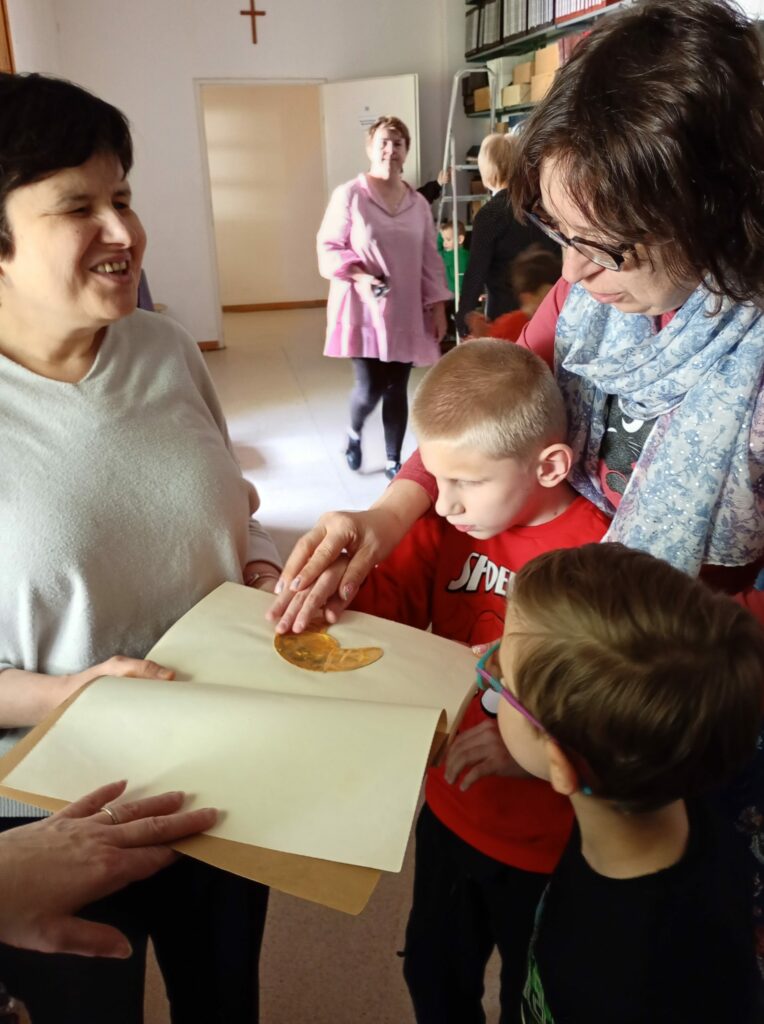 Chłopiec dotyka obrazka w książce, przy nim opiekunki