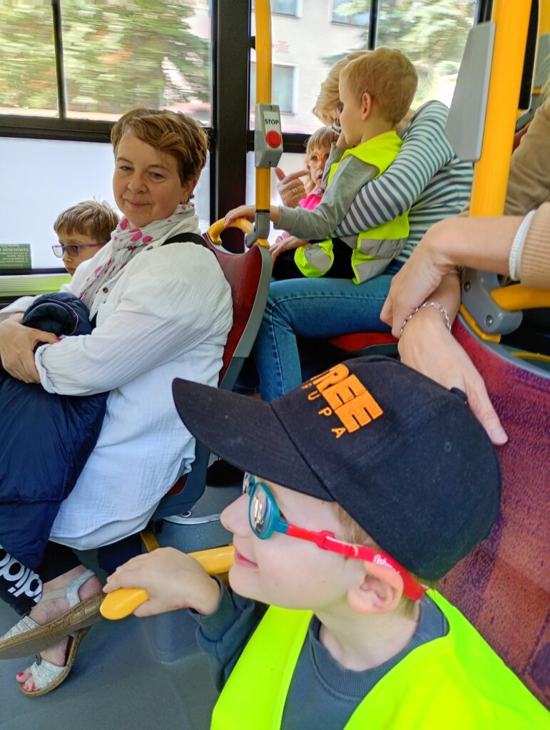 Dzieci i opiekunki siedzą w autobusie. 