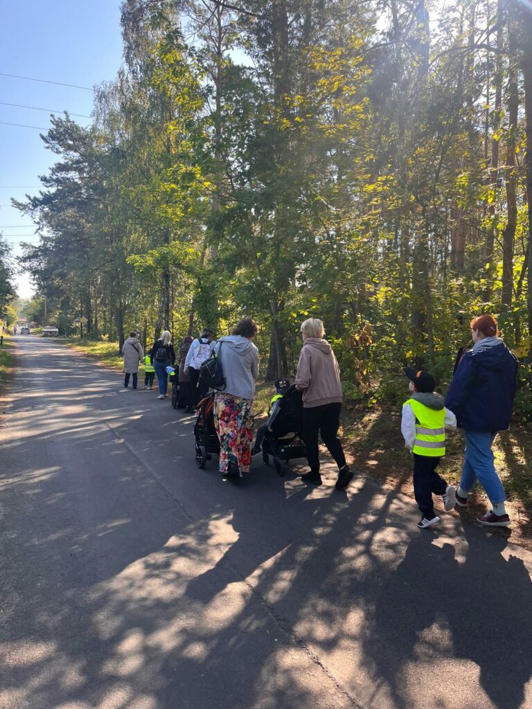Dzieci z nauczycielami idą ulicą. Dzieci mają na sobie odblaskowe kamizelki.
