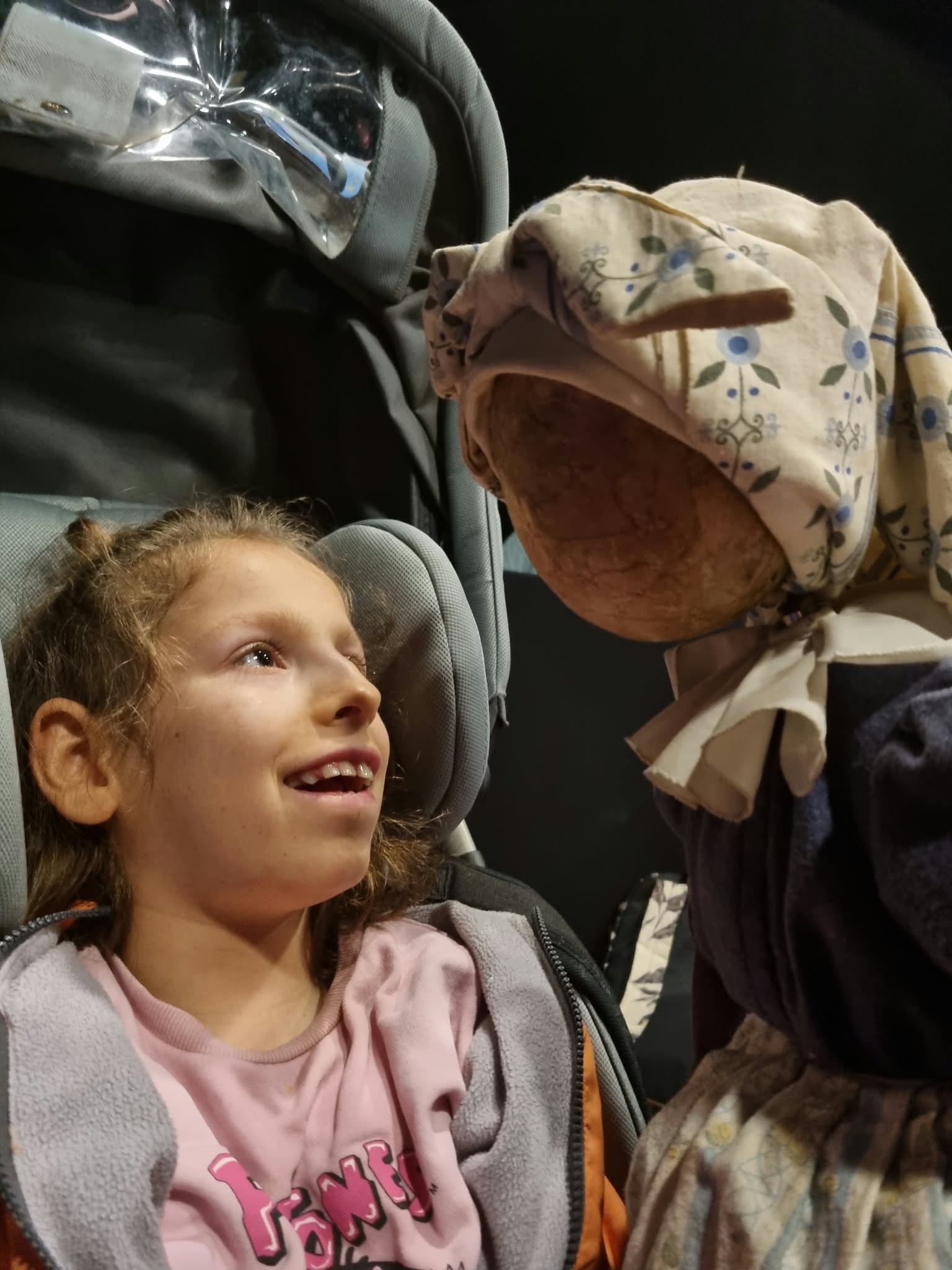 Uśmiechnięta uczennica na wózku nawiązuje bezpośredni kontakt z animowaną lalką teatralną